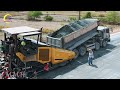 National road construction site. A dump truck process of unloading the gravel into a paver machine