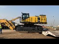 unloading this massive hydraulic excavator Komatsu pc 1250 from the trailer skilled operator.