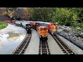 A Steam Train and Two Diesel Model Trains Running Outdoors On A Huge Outdoor Model Train Layout