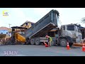 In the new road construction site, A large yellow gravel paving machine spreads the gravel process